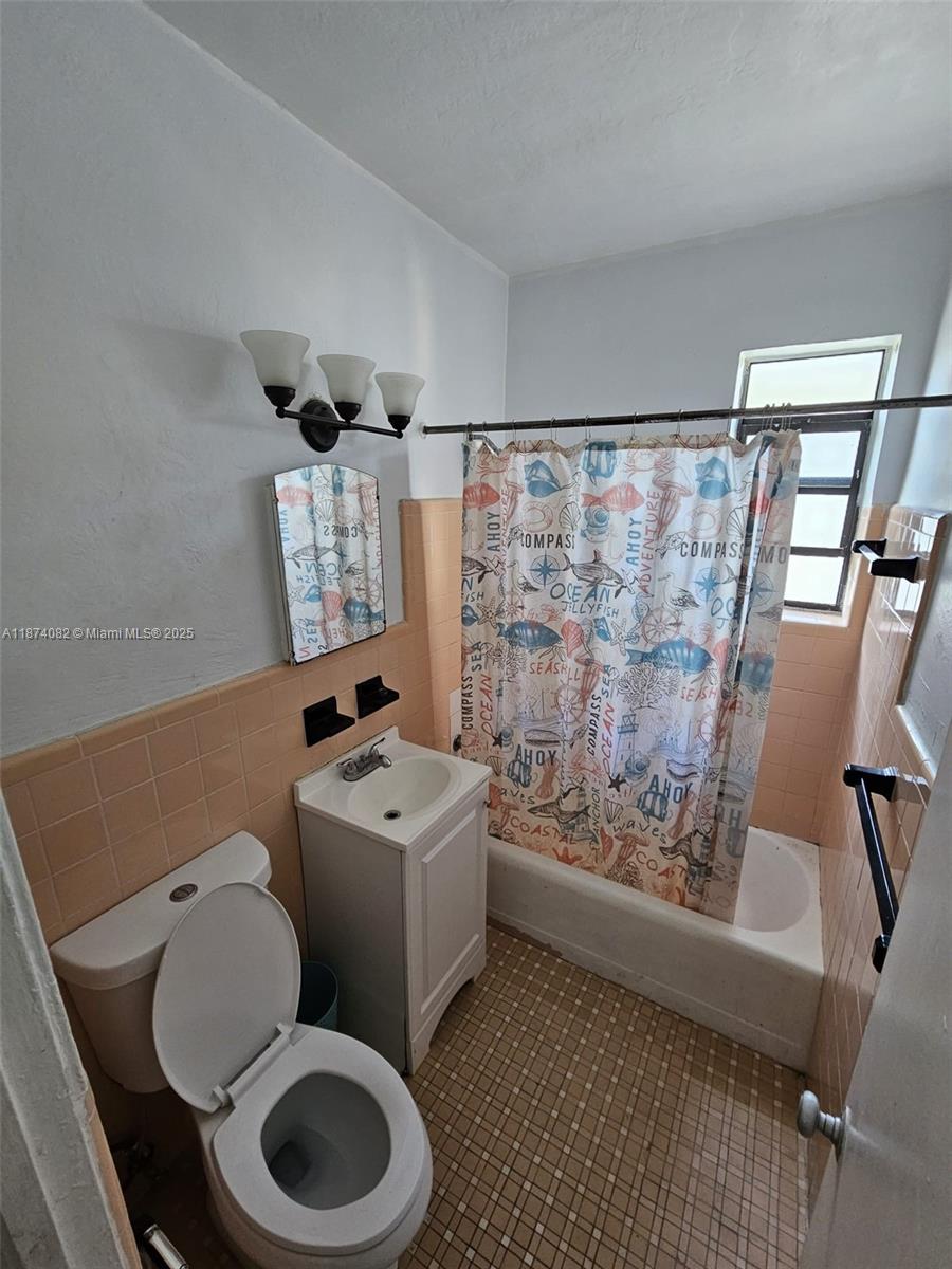 7320 Carlyle Avenue, Unit 4 Miami Beach, FL 33141 - Photo 4 of 8 a bathroom with a toilet sink and mirror