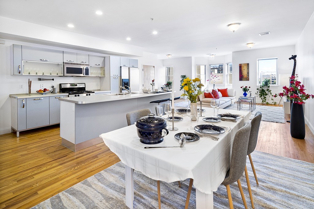 877 Harrison Avenue, Unit 7 Boston, MA 02118 - Photo 8 of 25 a kitchen with stainless steel appliances a dining table chairs microwave and stove top oven