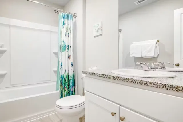 a bathroom with a granite countertop sink a toilet a mirror and shower
