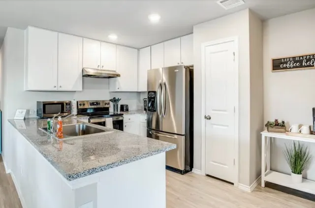 a kitchen with stainless steel appliances granite countertop a refrigerator a stove a sink and a granite counter tops