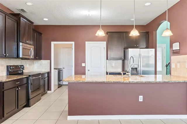 a kitchen with stainless steel appliances granite countertop a refrigerator and a stove top oven