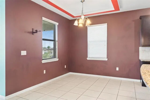 a view of an empty room with window and chandelier fan