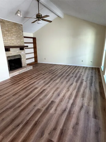 an empty room with a fireplace and wooden floor