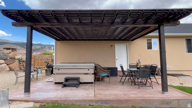 1797 Sunset Road Enoch, UT 84721 - Photo 56 of 80 Expansive concrete patio featuring a dark-stained wood pergola, stucco exterior, and a built-in spa