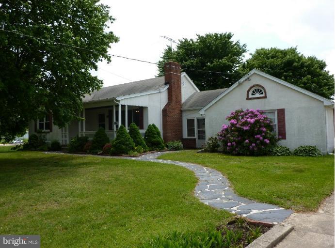 a view of a white house with a yard and potted plants