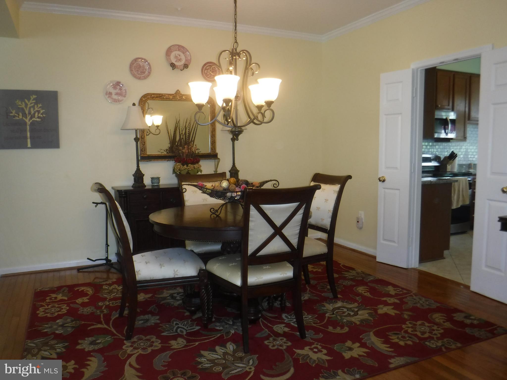 2444 Rippling Brook Road Frederick, MD 21701 - Photo 10 of 49 a dining room with wooden floor a chandelier a wooden table and chairs