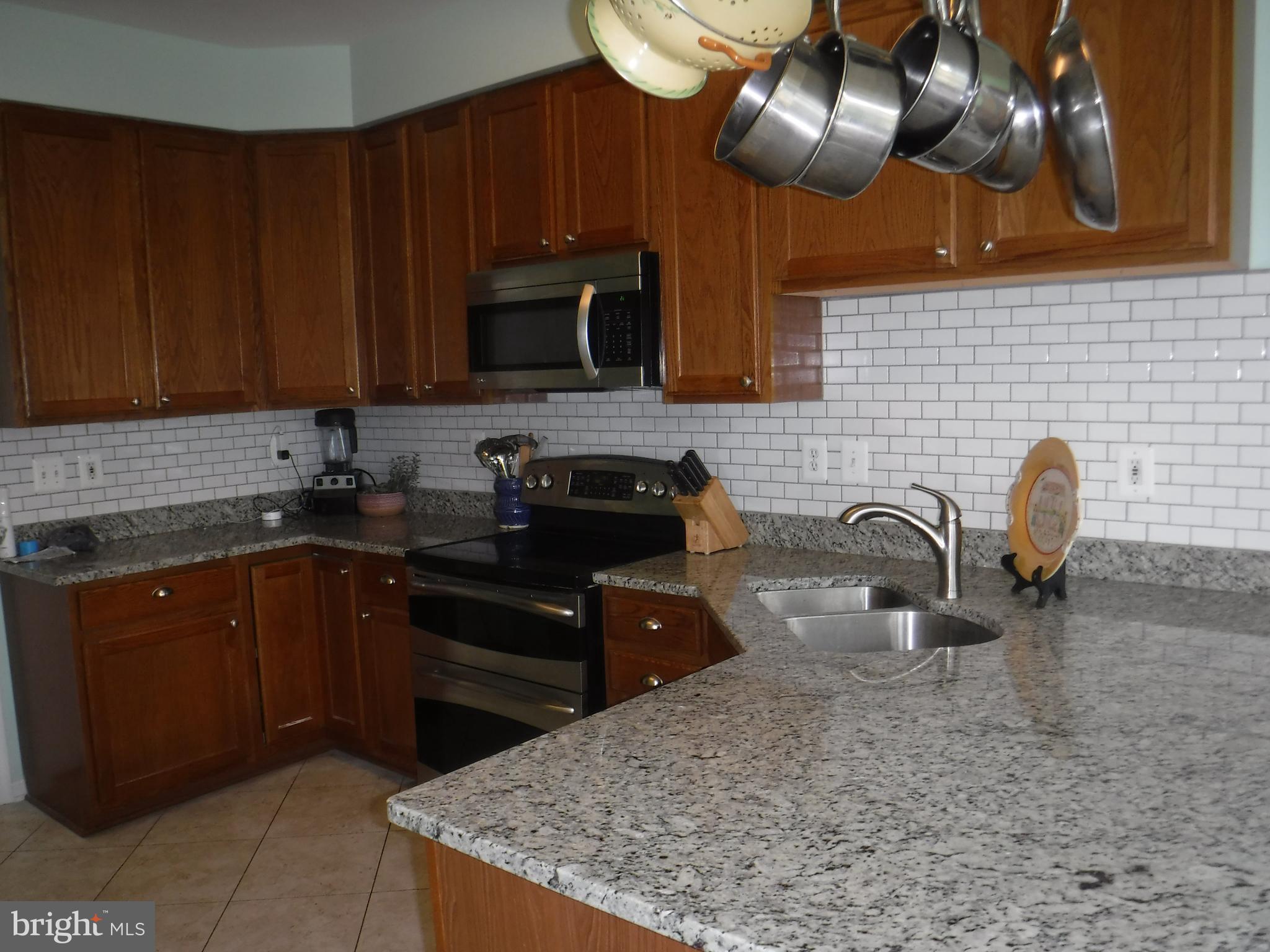 2444 Rippling Brook Road Frederick, MD 21701 - Photo 14 of 49 a kitchen with stainless steel appliances granite countertop a sink dishwasher a stove a refrigerator a microwave oven with granite countertops and cabinets