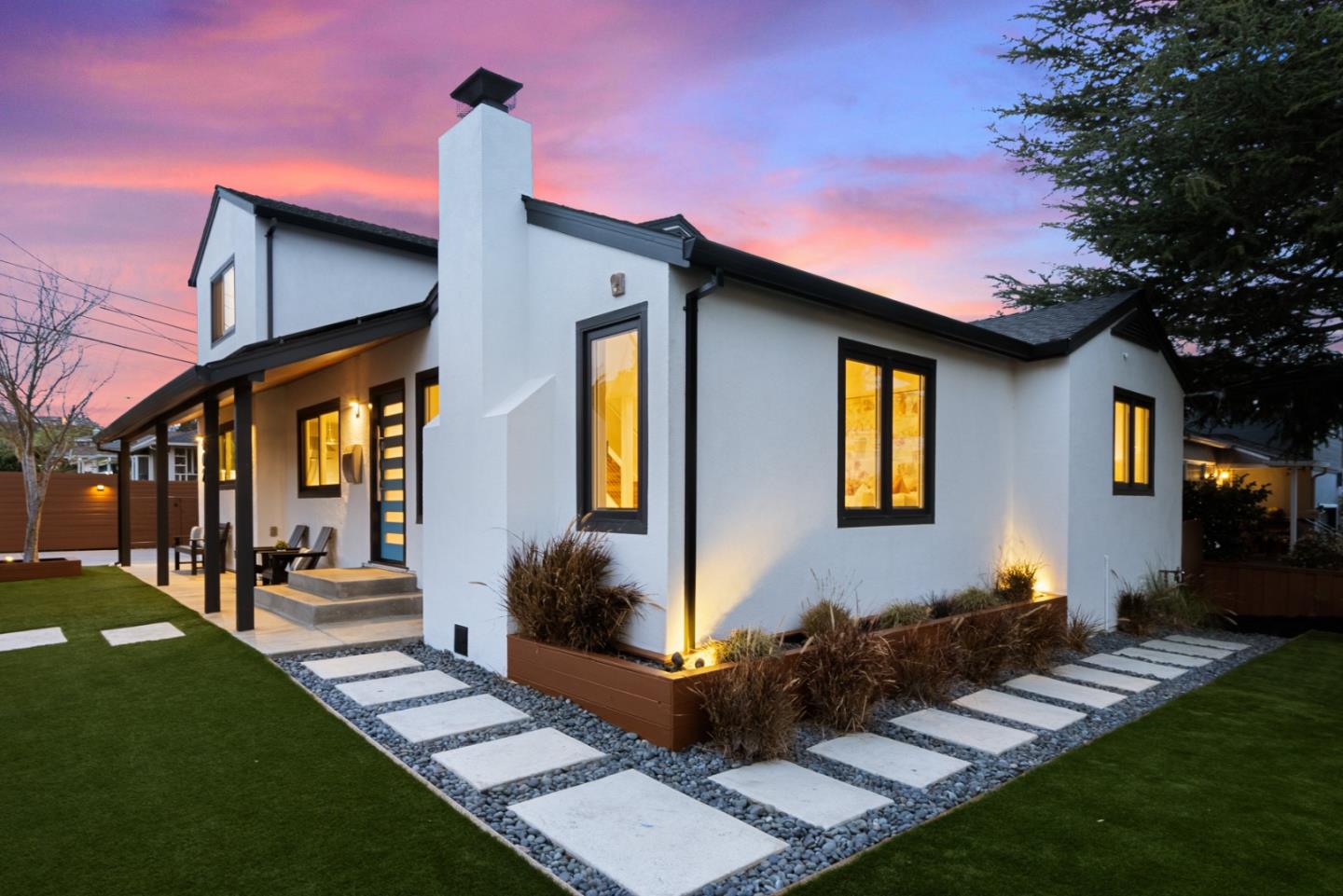 a front view of a house with a yard outdoor seating and covered with trees