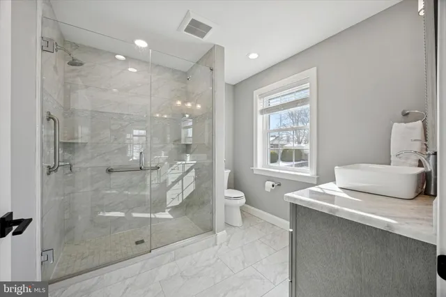 a bathroom with a granite countertop sink a toilet and shower