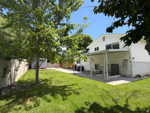 375 East 10560 South Sandy, UT 84070 - Photo 16 of 21 Expansive green lawn with a mature shade tree, concrete patio, and covered outdoor living area