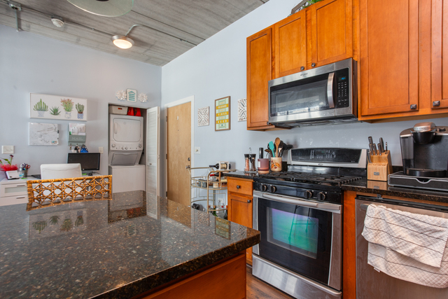 1228 West Monroe Street, Unit 407 Chicago, IL 60607 - Photo 5 of 15 a kitchen with stainless steel appliances granite countertop a stove top oven a sink dishwasher and microwave with wooden floor