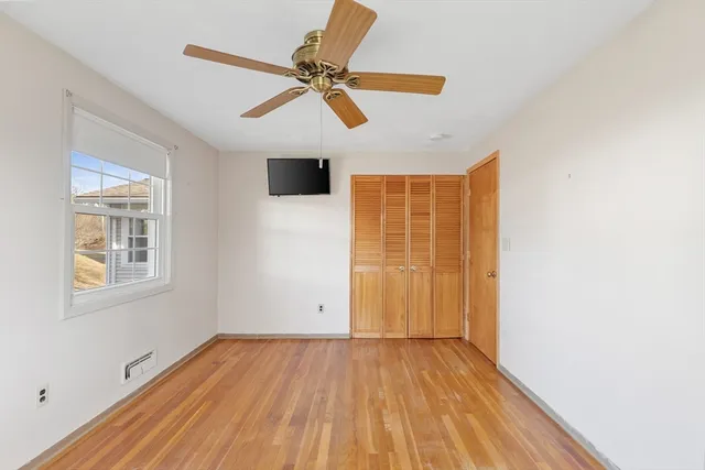 a view of empty room with wooden floor and fan