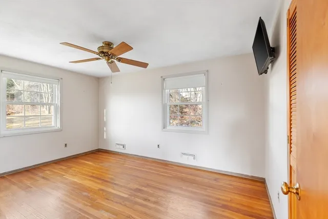 a view of empty room with wooden floor and fan