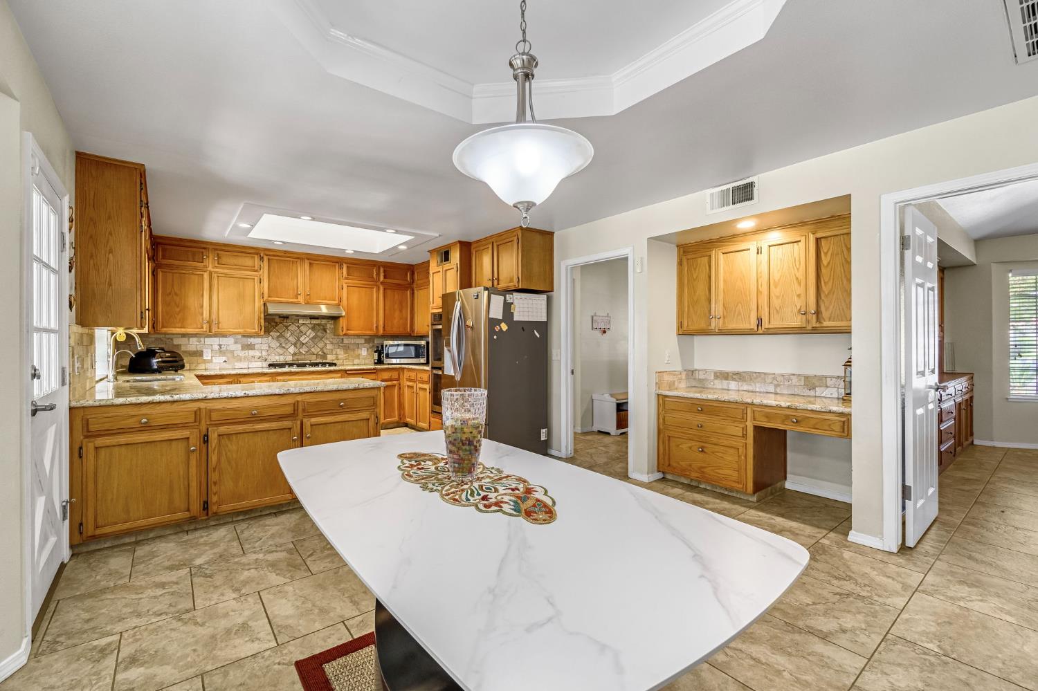 2436 Trevor Court Madera, CA 93637 - Photo 15 of 57 a kitchen with stainless steel appliances kitchen island granite countertop a sink refrigerator dining table and chairs