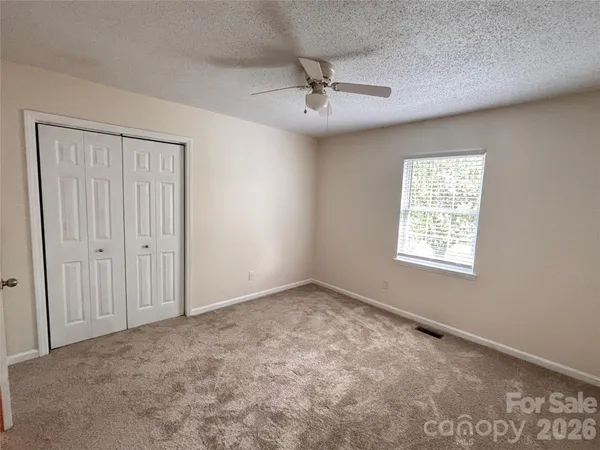 an empty room with windows and fan