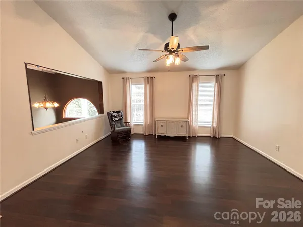 a view of an empty room with window and wooden floor