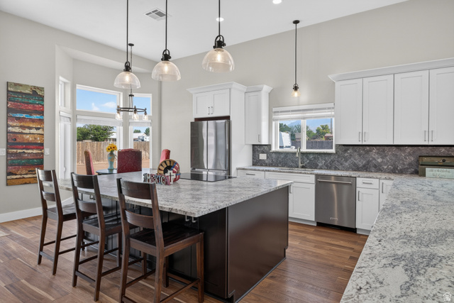 4297 Beeman Road Moab, UT 84532 - Photo 8 of 59 Contemporary kitchen featuring an expansive center island with seating, stainless steel appliances, white cabinetry, and wood-finish flooring