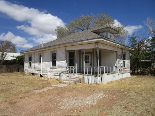 a patio with a table and chairs and potted plants