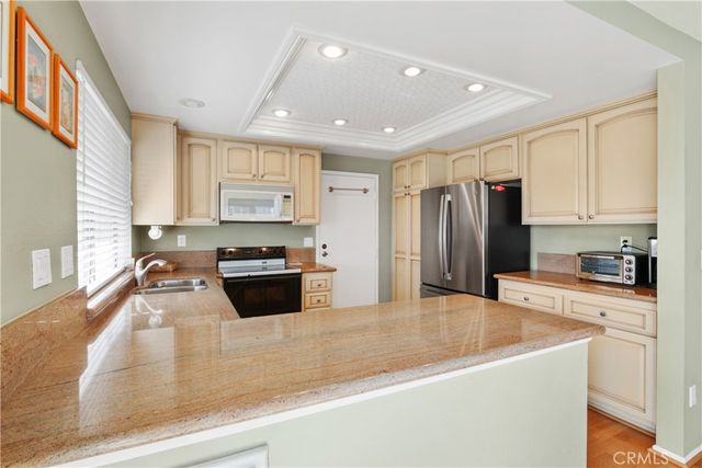 a kitchen with granite countertop a refrigerator a sink a stove and wooden cabinets