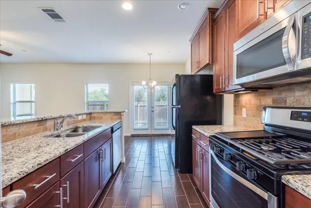 a kitchen with stainless steel appliances granite countertop a stove refrigerator and microwave