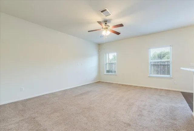 an empty room with windows and fan