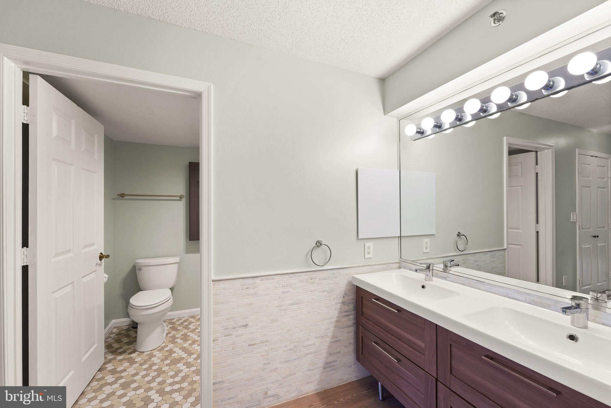 19385 Cypress Ridge Terrace, Unit 522 Leesburg, VA 20176 - Photo 27 of 33 a spacious bathroom with a double vanity sink a toilet and a shower