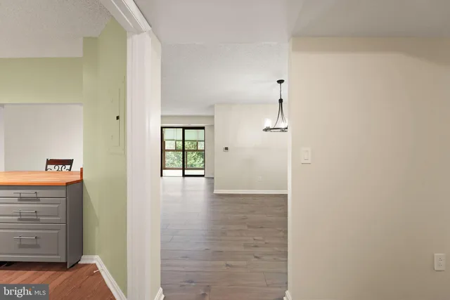 a view of a hallway with wooden floor and a bathroom
