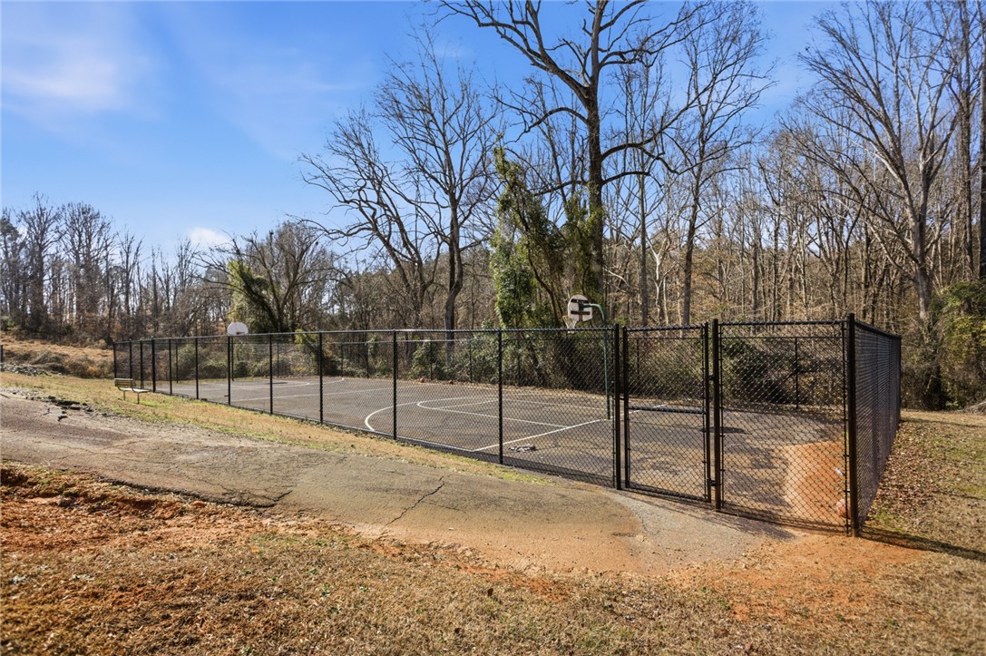 108 Hodge Street Abbeville, SC 29620 - Photo 28 of 39 An outdoor basketball court enclosed by a fence, ready for play amidst natural surroundings.