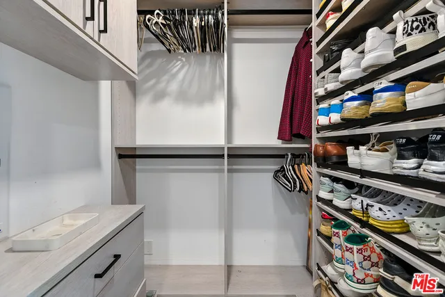a view of walk in closet with clothes and shoes