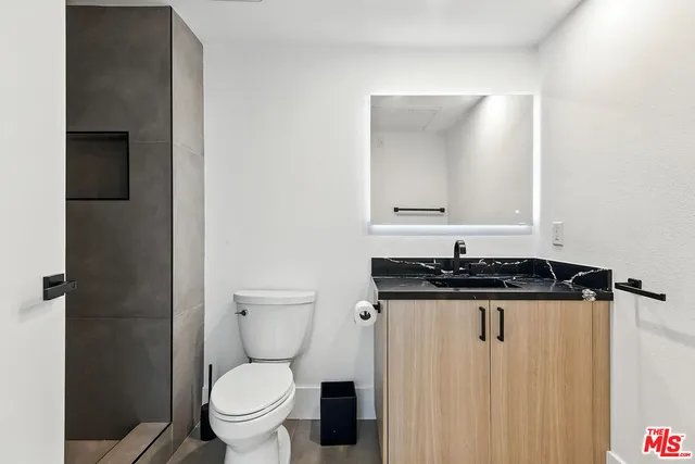 a bathroom with a granite countertop sink a toilet and a mirror