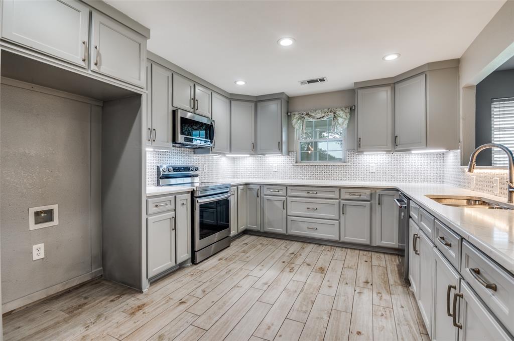 155 Smith Lane Combine, TX 75159 - Photo 8 of 31 Kitchen with stainless steel appliances, gray cabinets, light stone counters, light wood-style (ceramic tile) flooring, and recessed lighting