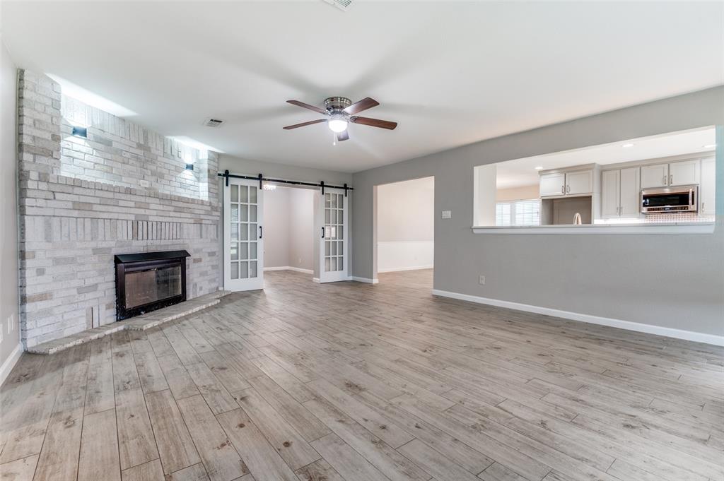 155 Smith Lane Combine, TX 75159 - Photo 9 of 31 Unfurnished living room with sliding doors into office, a fireplace, ceiling fan, and light ceramic tile