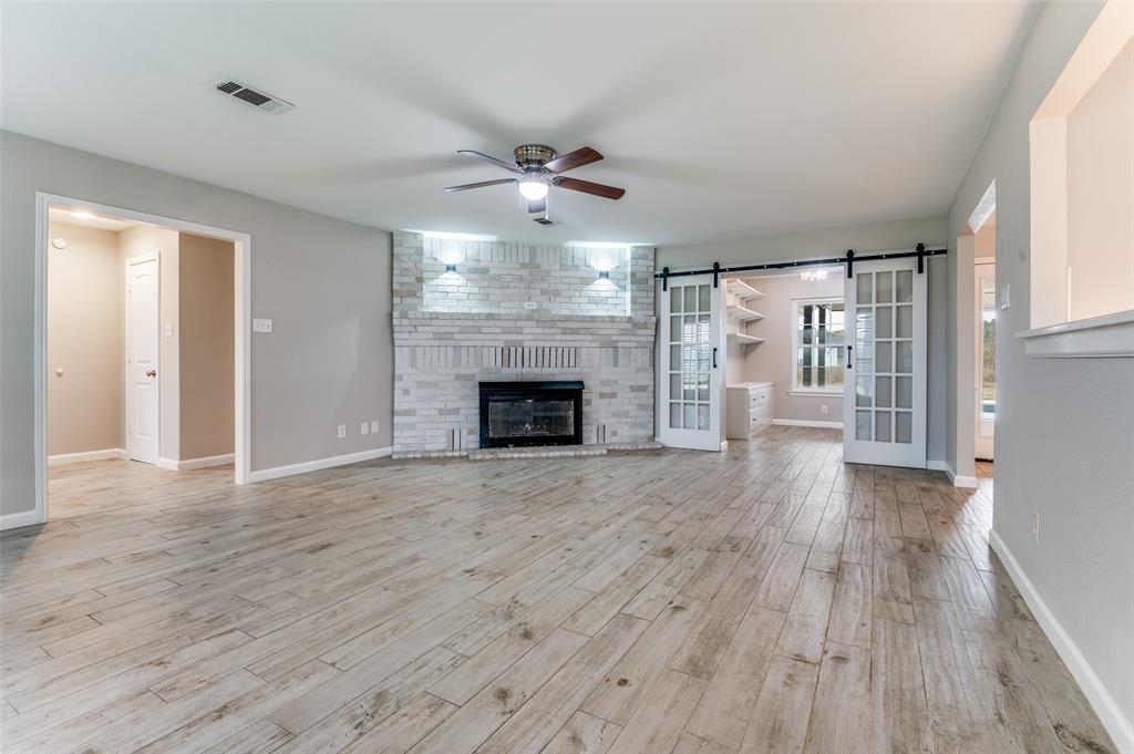 155 Smith Lane Combine, TX 75159 - Photo 10 of 31 Unfurnished living room featuring a barn door, a fireplace, a ceiling fan, and light ceramic tile wood-style flooring