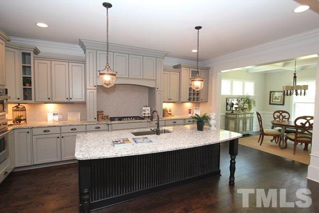 1221 Harrison Ridge Road Wake Forest, NC 27587 - Photo 6 of 25 a large kitchen with kitchen island a stove a sink a center island a dining table and chairs with wooden floor