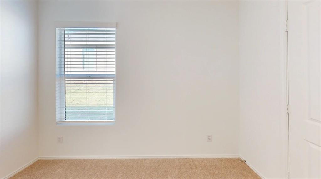 9757 Platteview Road Fort Worth, TX 76179 - Photo 9 of 19 Neutral interior room featuring a single window with horizontal blinds, light-colored walls, and beige carpet flooring