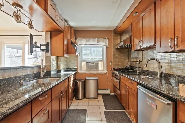 a kitchen with stainless steel appliances granite countertop a sink a stove and a wooden cabinets
