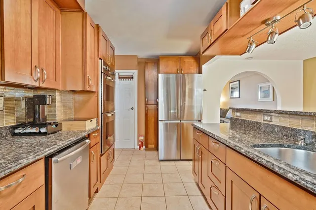 a kitchen with stainless steel appliances granite countertop a sink and a refrigerator