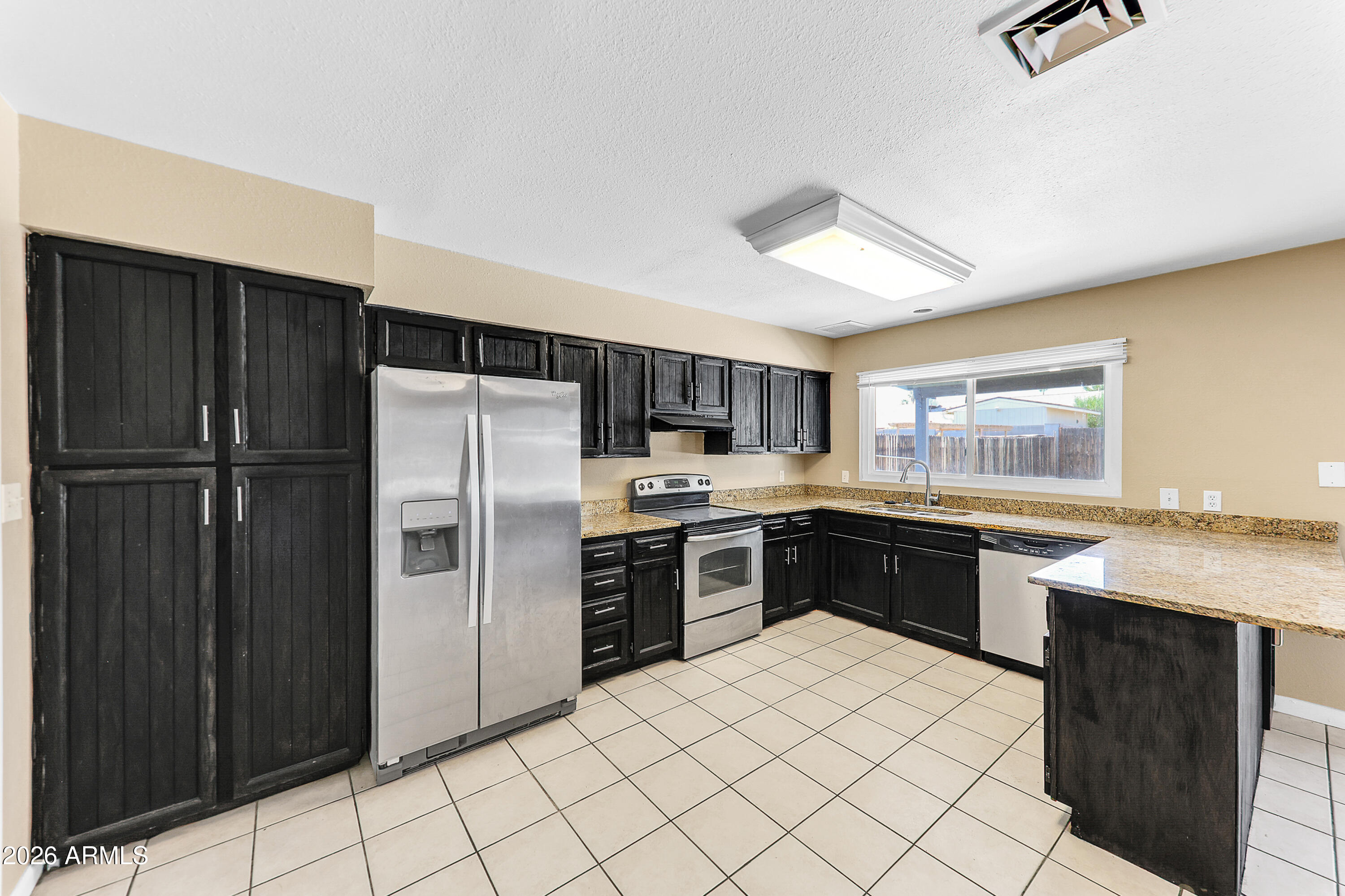 4723 East Vineyard Road Phoenix, AZ 85042 - Photo 11 of 27 a kitchen with stainless steel appliances granite countertop a refrigerator and a stove top oven