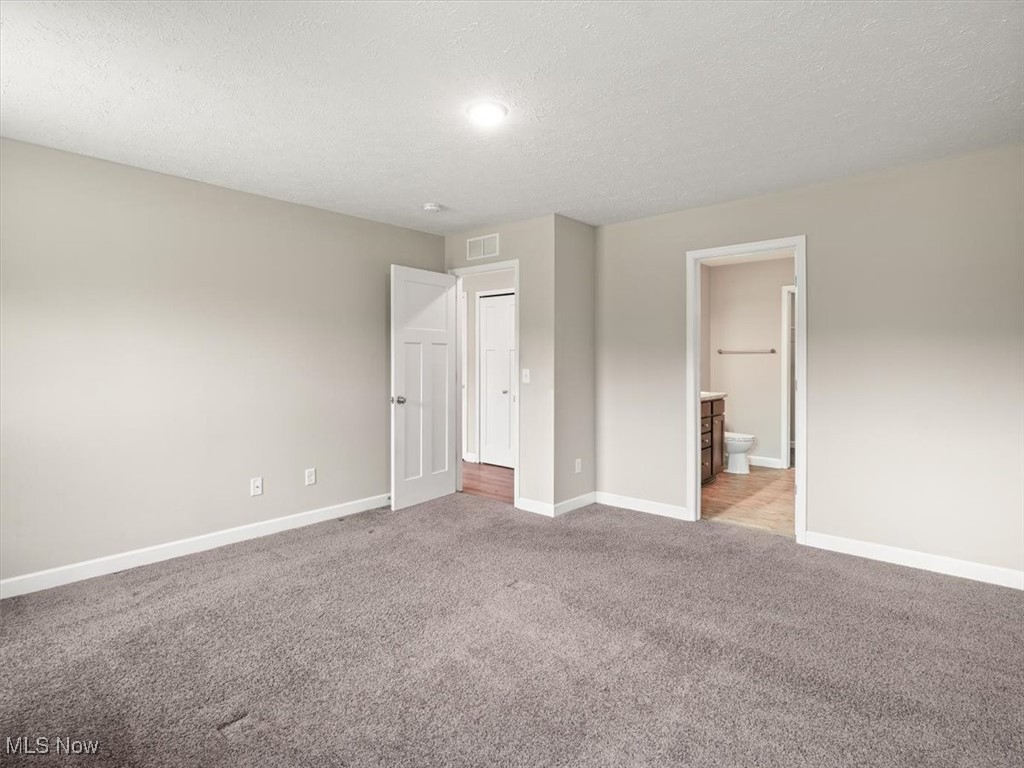 5525 White Road Geneva, OH 44041 - Photo 26 of 28 Unfurnished bedroom featuring ensuite bath, a textured ceiling, and light colored carpet