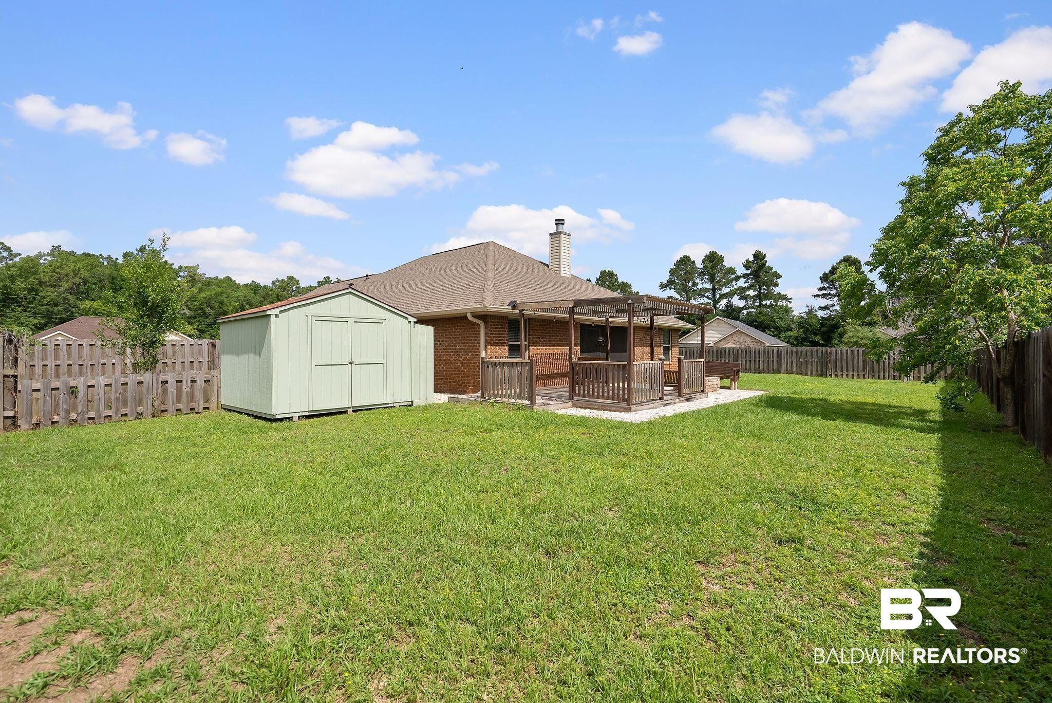 22076 Garland Loop Silverhill, AL 36576 - Photo 24 of 27 Generous backyard featuring a wooden privacy fence, a detached storage shed, and a covered patio with a pergola