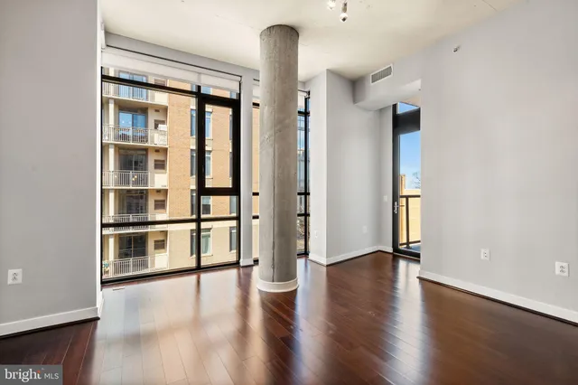 a view of an empty room with a window and wooden floor