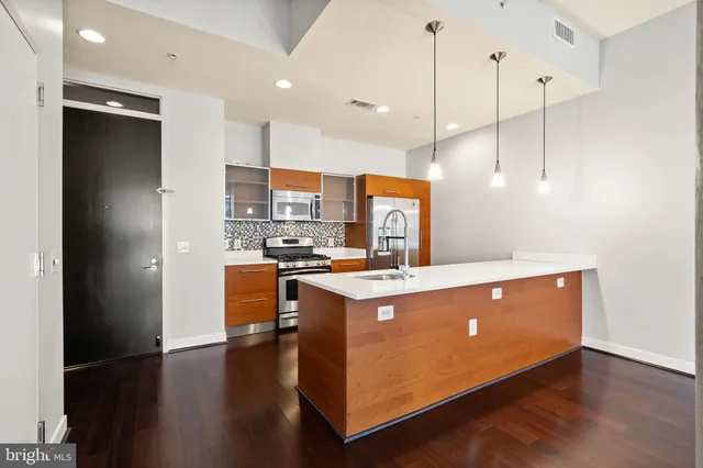 a open kitchen with stainless steel appliances granite countertop a stove a refrigerator a sink and a wooden floor