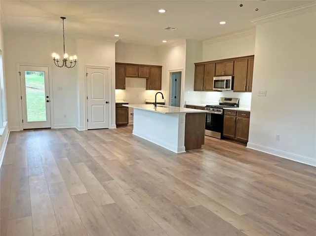 a large kitchen with stainless steel appliances granite countertop a large center island a stove a refrigerator and a view of living room