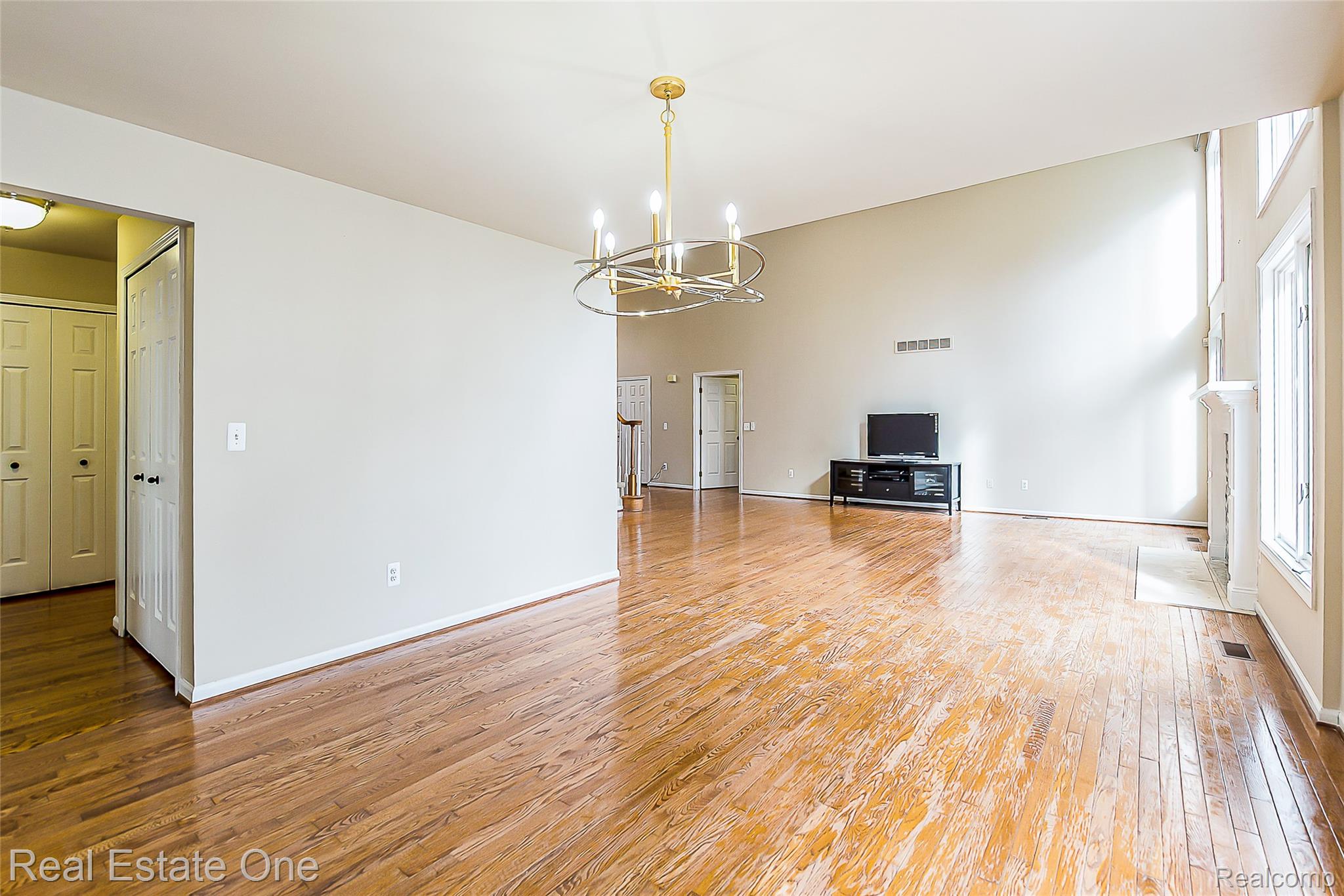 1013 Rochelle Park Drive Rochester, MI 48307 - Photo 13 of 74 Vaulted ceiling, wood-finish flooring, contemporary chandelier, fireplace with mantel, and window bank