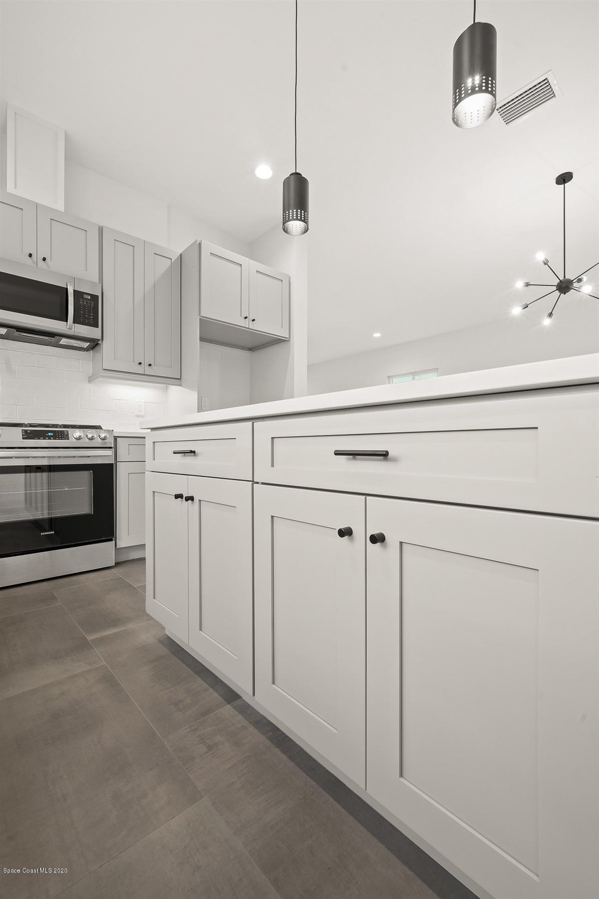 2168 Country Club Road Melbourne, FL 32901 - Photo 19 of 94 a kitchen with white cabinets and white appliances