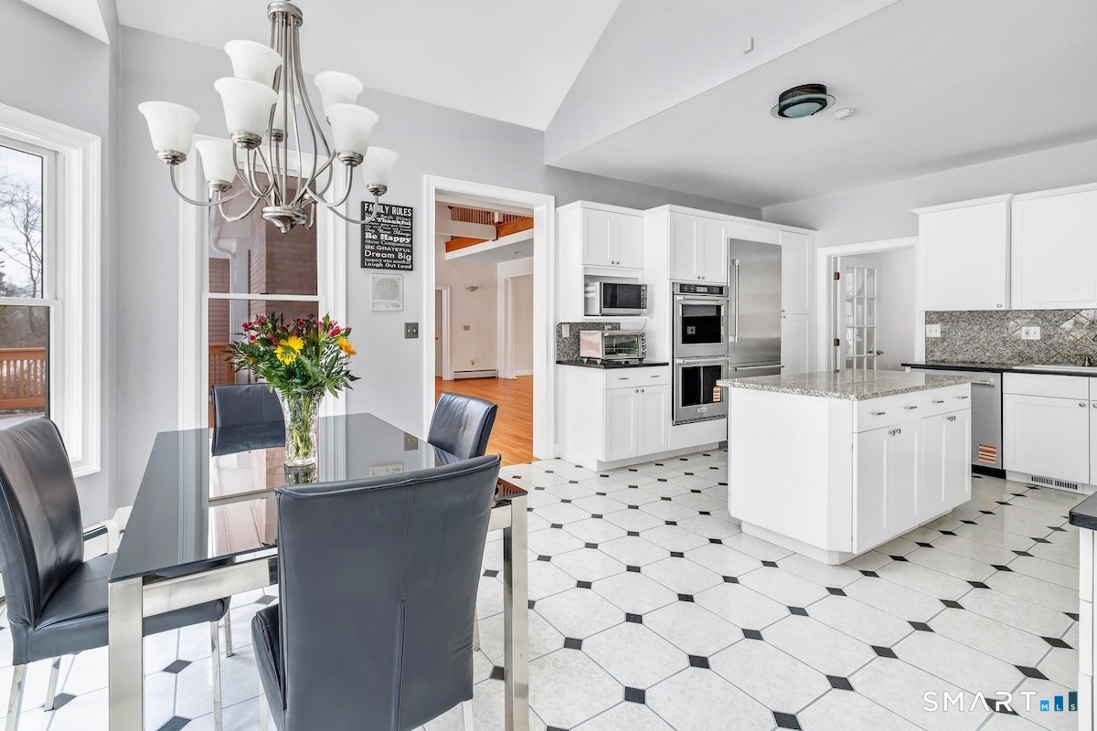 461 Amity Road Woodbridge, CT 06525 - Photo 17 of 40 a kitchen with stainless steel appliances kitchen island granite countertop a refrigerator a sink dishwasher a dining table and chairs with wooden floor