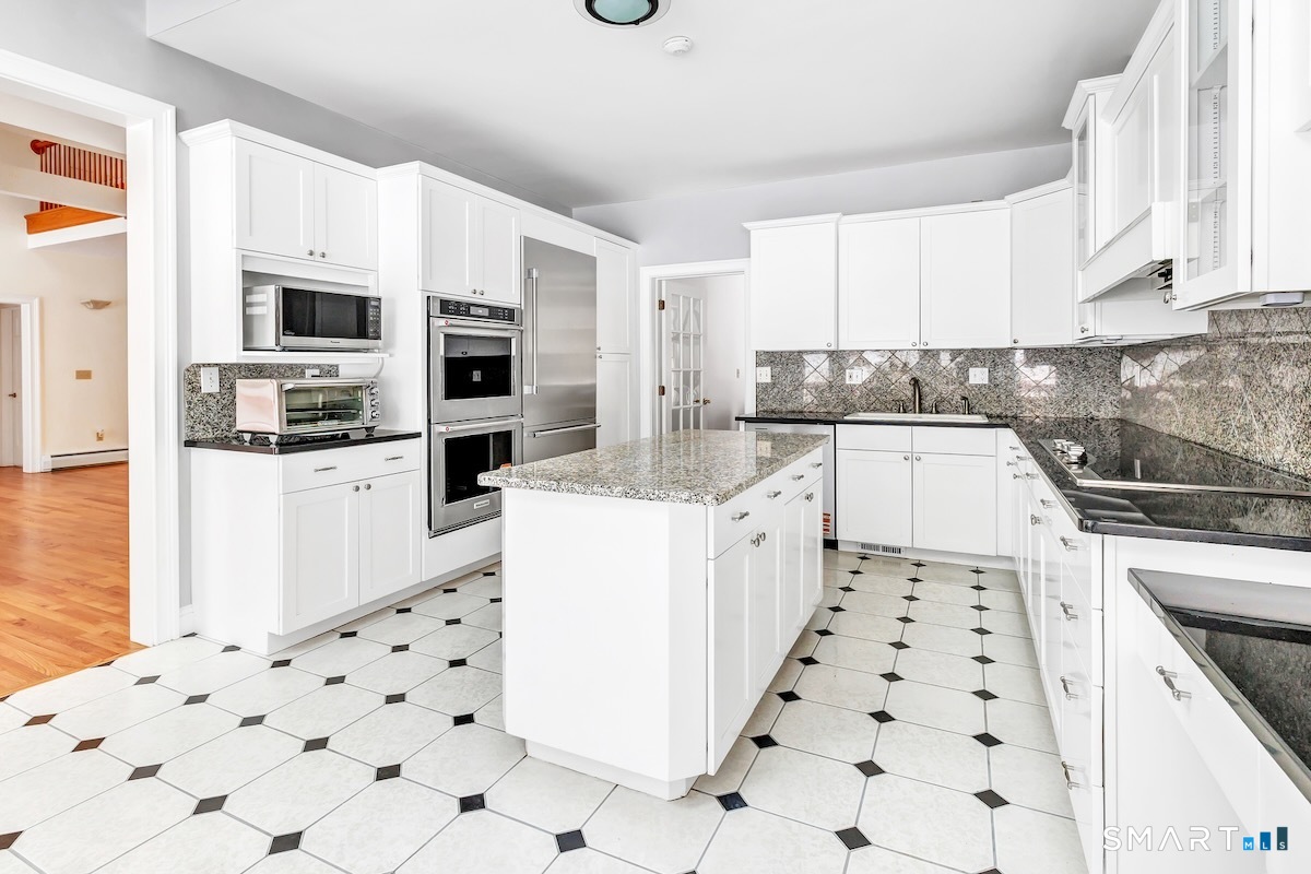 461 Amity Road Woodbridge, CT 06525 - Photo 18 of 40 a kitchen with granite countertop a refrigerator sink and white cabinets