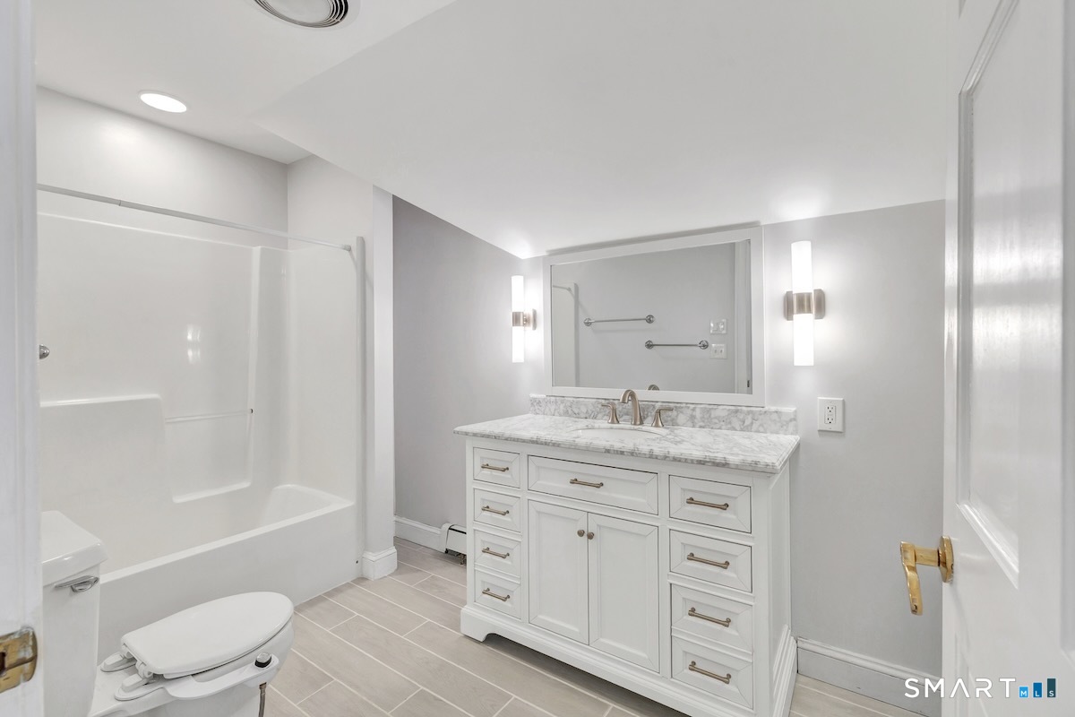 461 Amity Road Woodbridge, CT 06525 - Photo 33 of 40 a bathroom with a granite countertop sink a toilet a mirror and a bathtub