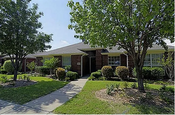 a front view of a house with garden and trees