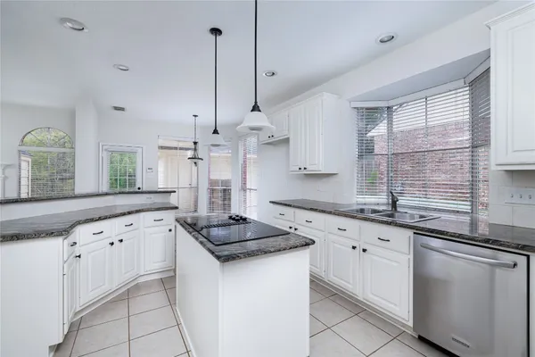 a kitchen with granite countertop white cabinets white appliances a sink and a window